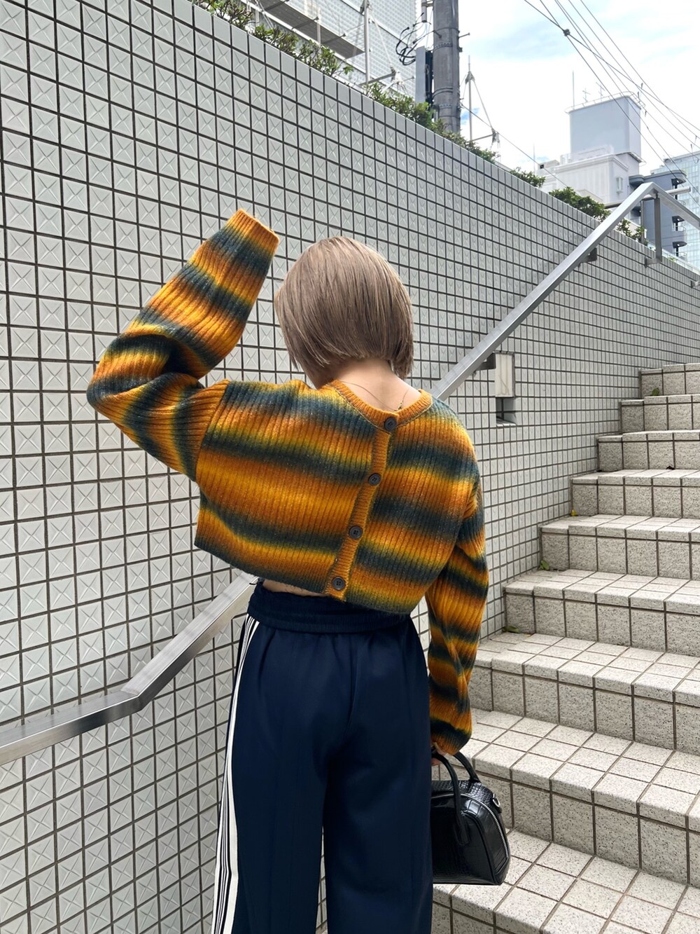 パープル系のカーディガン/ボレロ、ブラック系のブーツ、ブルー系のその他パンツを着用したレディースの秋コーディネートの6枚目の写真