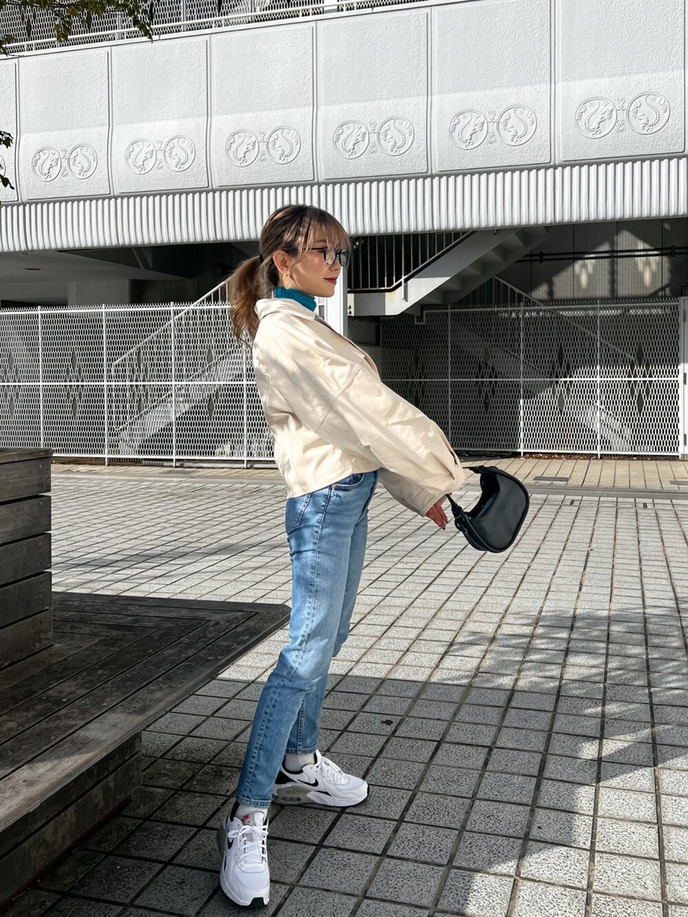 ホワイト系のライダースジャケット、ブルー系のニット/セーター、ブラック系のハンドバッグを着用したレディースの冬コーディネートの4枚目の写真