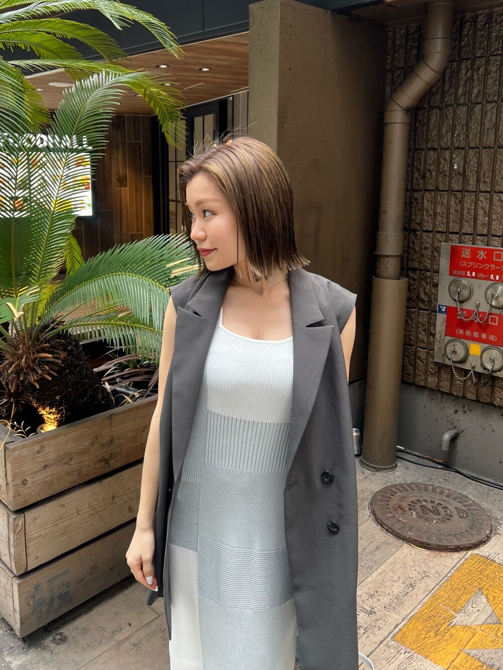 ホワイト系のワンピース、グレー系のベスト、ブラック系のサンダルを着用したレディースの春コーディネートの4枚目の写真