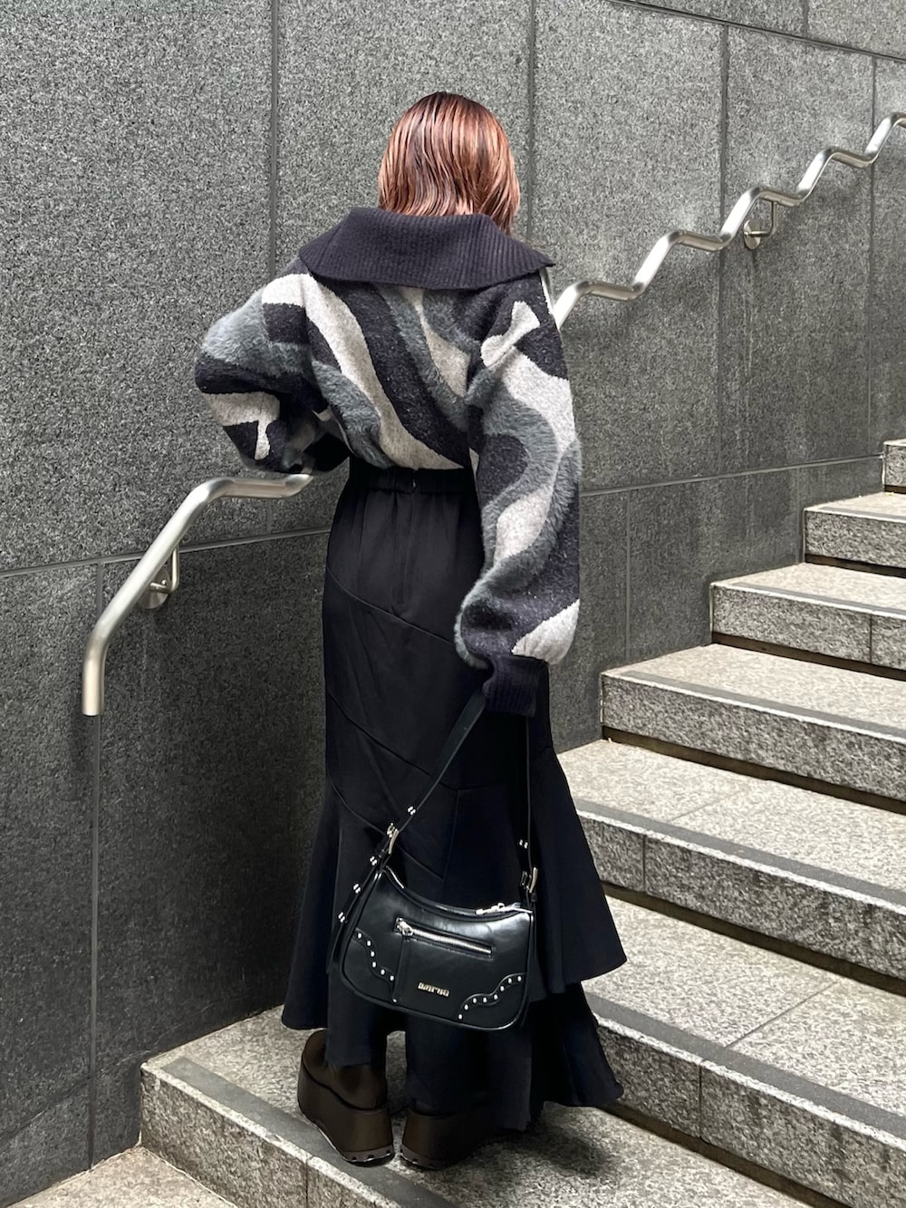 ブラック系のニット/セーター、ブラウン系のブーツ、ブラック系のスカートを着用したレディースの秋コーディネートの4枚目の写真