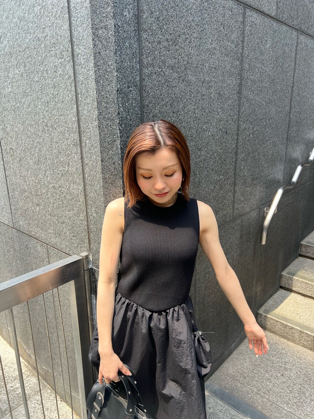 ブラック系のワンピース、ブラック系のサンダル、ブラック系のハンドバッグを着用したレディースの夏コーディネートの4枚目の写真