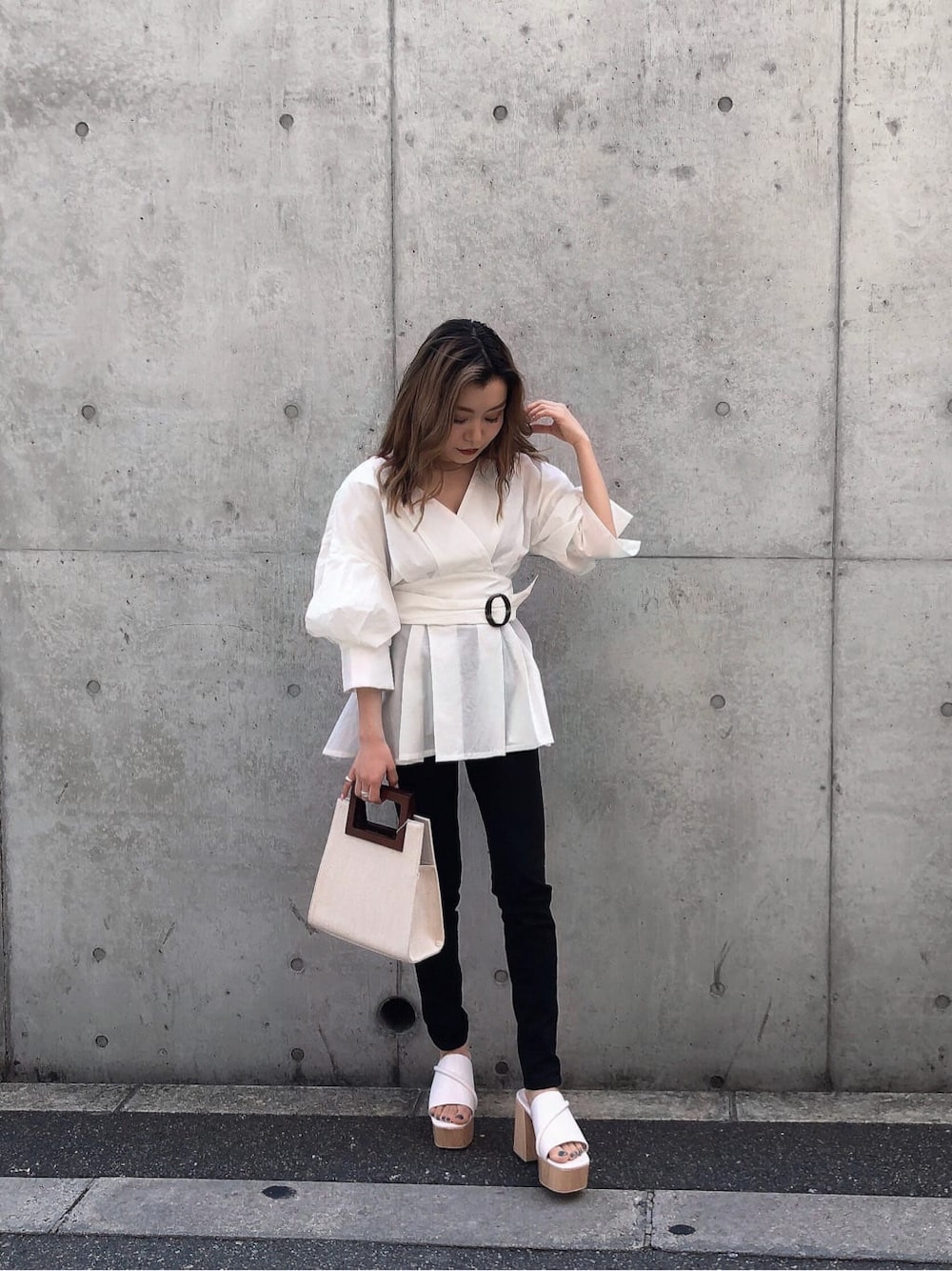 ホワイト系のサンダル、ブラック系のデニムパンツ、ホワイト系のハンドバッグを着用したレディースの春コーディネートの2枚目の写真