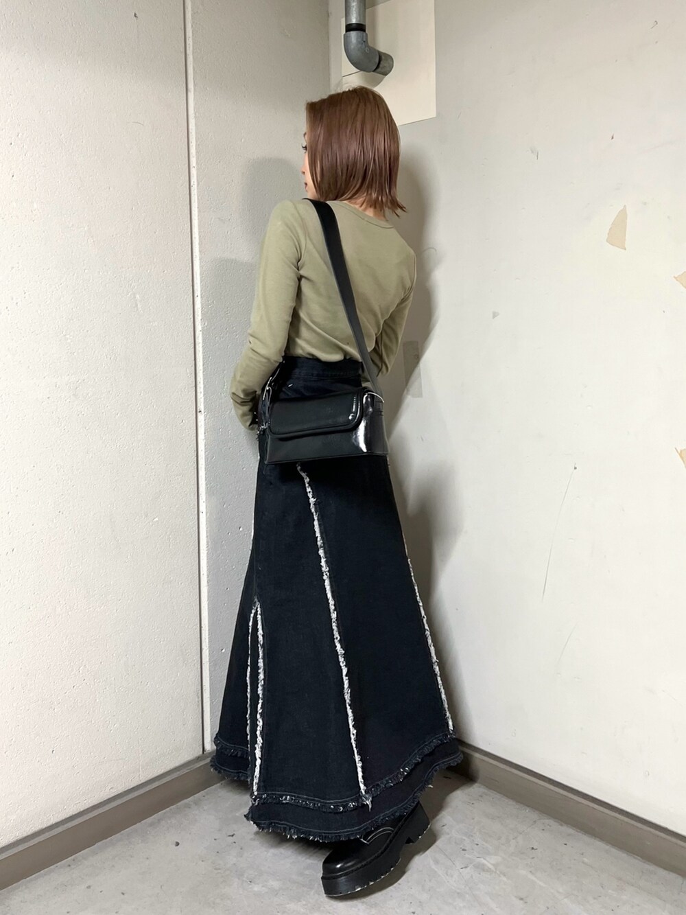 グリーン系のTシャツ/カットソー、ブラック系のデニムスカート、ブラック系のブーツを着用したレディースの冬コーディネートの3枚目の写真