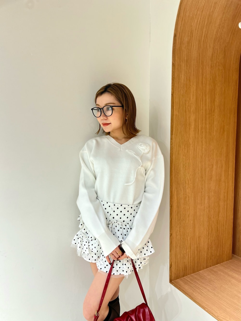 ホワイト系のニット/セーター、ホワイト系のその他パンツ、レッド系のハンドバッグを着用したレディースの冬コーディネートの4枚目の写真