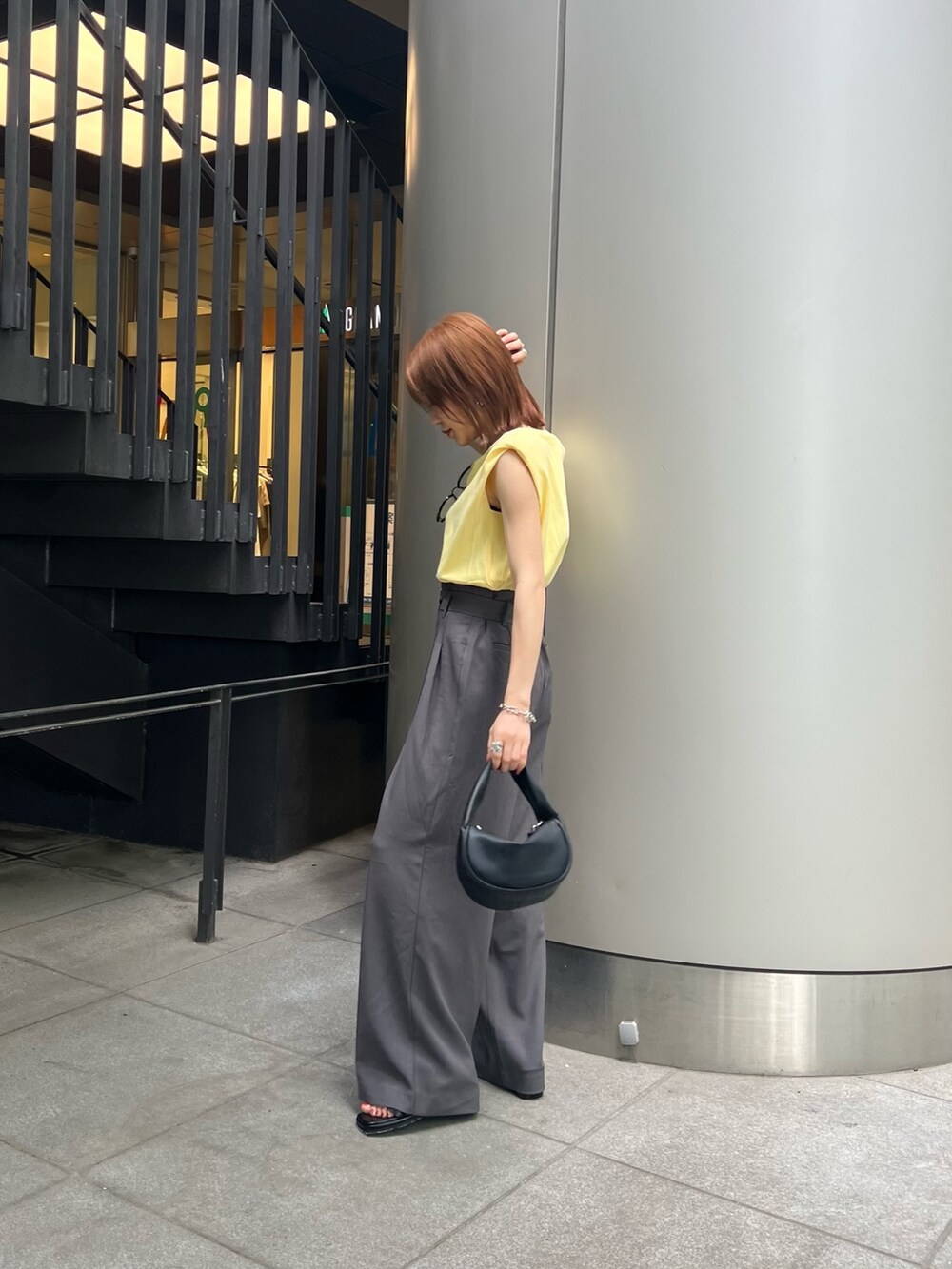 ブラック系のサンダル、グレー系のスラックス、イエロー系のTシャツ/カットソーを着用したレディースの春コーディネートの4枚目の写真