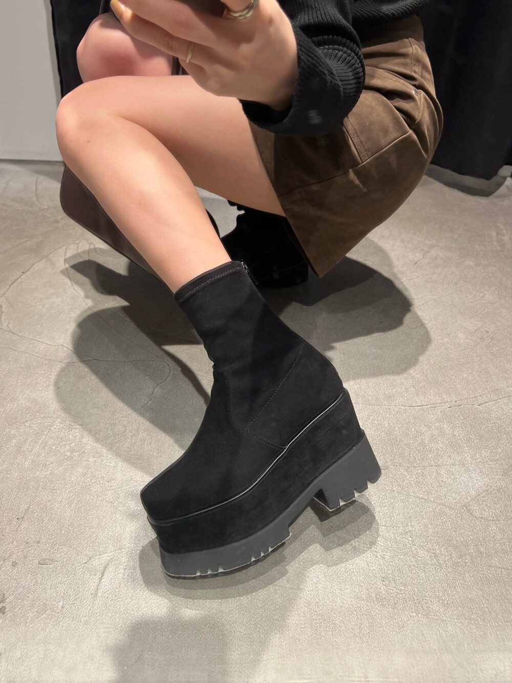 ブラック系のブーツ、ブラウン系のスカート、ブラック系のニット/セーターを着用したレディースの冬コーディネートの8枚目の写真