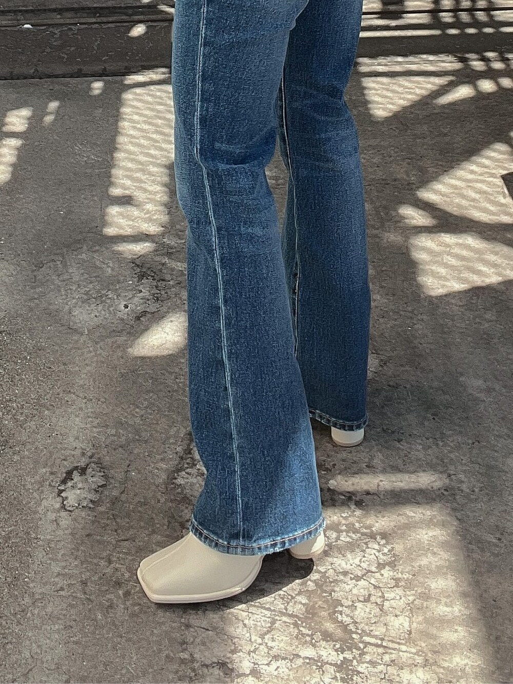 ブルー系のデニムパンツ、オレンジ系のニット/セーター、ホワイト系のブーツを着用したレディースの夏コーディネートの8枚目の写真