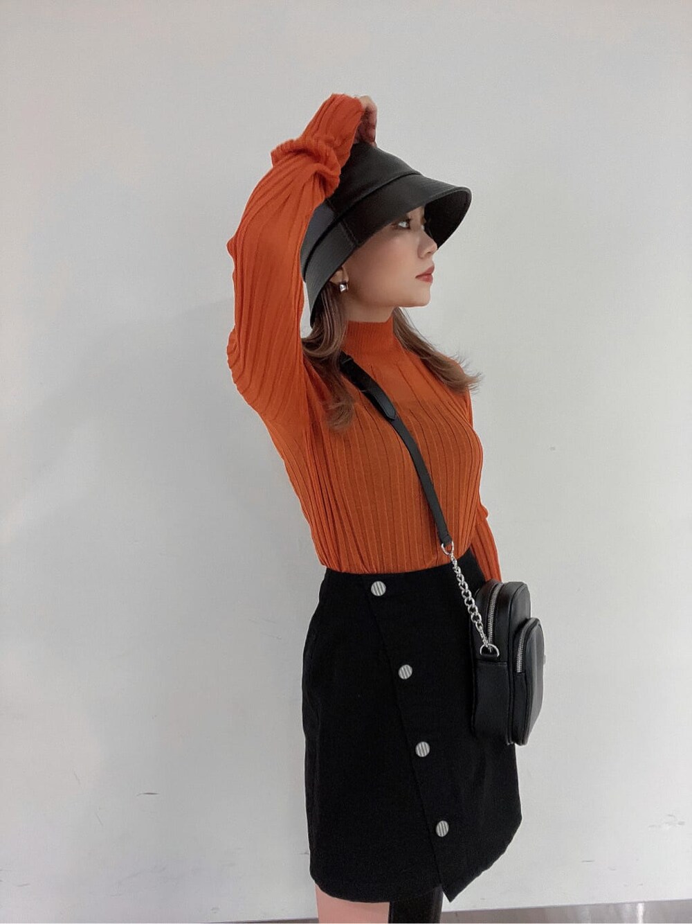 ブラック系のブーツ、オレンジ系のニット/セーター、ブラック系のスカートを着用したレディースの秋コーディネートの2枚目の写真