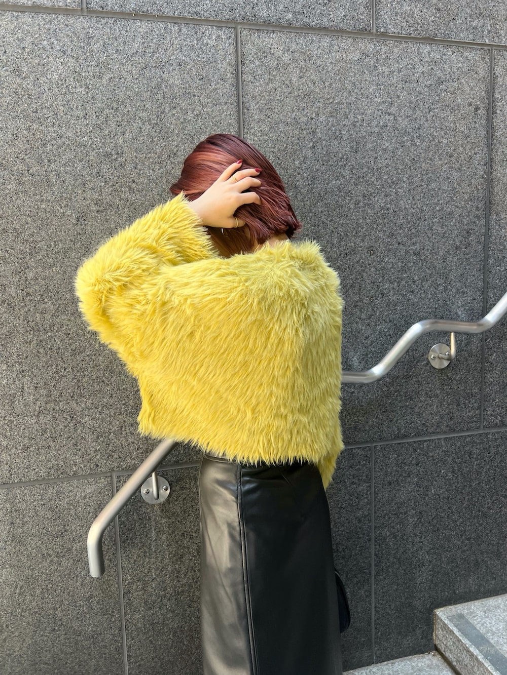 イエロー系のニット/セーター、ブラック系のスカート、ブラック系のブーツを着用したレディースの秋コーディネートの6枚目の写真