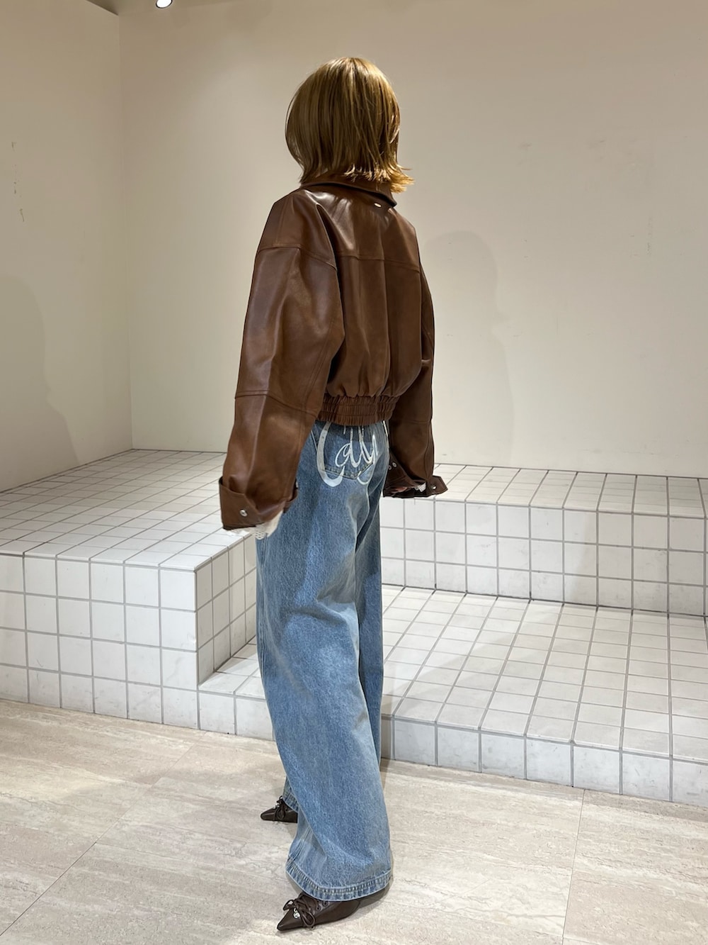 イエロー系のTシャツ/カットソー、ブルー系のその他パンツ、ブラウン系のブルゾンを着用したレディースの冬コーディネートの2枚目の写真