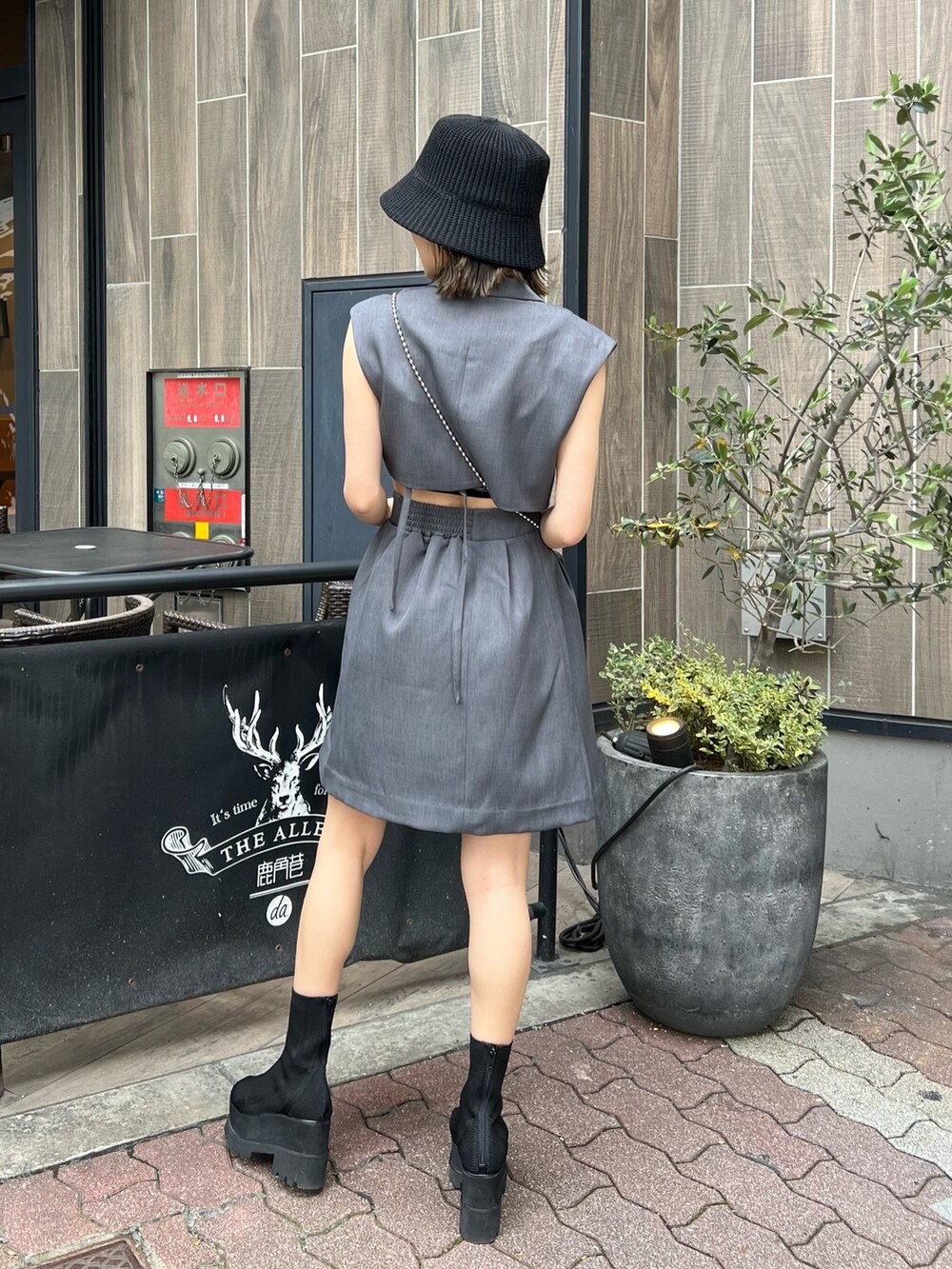 グレー系のワンピース、ブラック系のショルダーバッグ、ブラック系のブーツを着用したレディースの春コーディネートの2枚目の写真