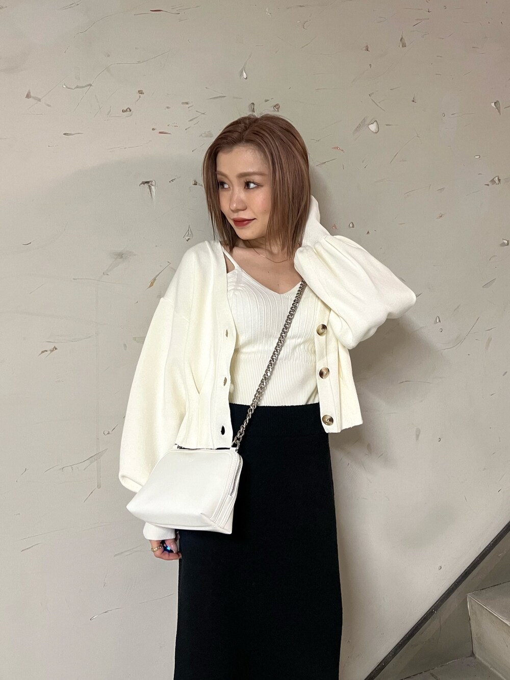 ホワイト系のブーツ、ブラック系のスカート、ホワイト系のカーディガン/ボレロを着用したレディースの冬コーディネートの6枚目の写真