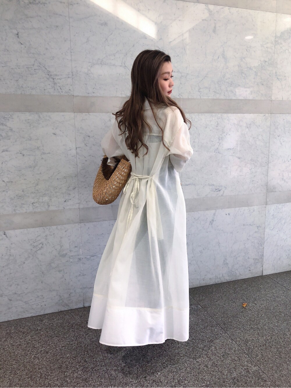 ホワイト系のキャミソール、ベージュ系のかごバッグ、ブルー系のデニムパンツを着用したレディースの春コーディネートの3枚目の写真