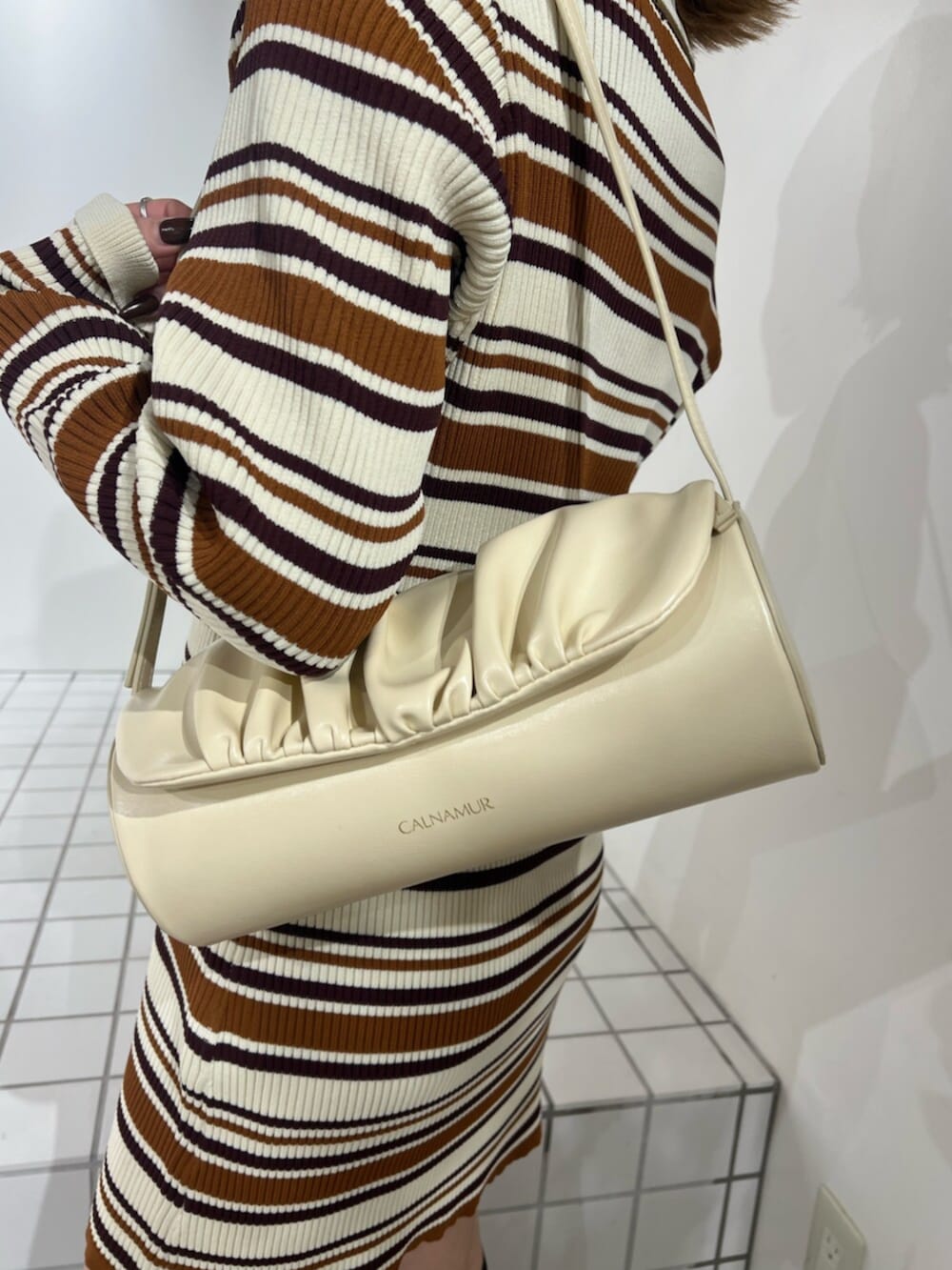 イエロー系のハンドバッグ、ブラウン系のワンピースを着用したレディースの冬コーディネートの5枚目の写真