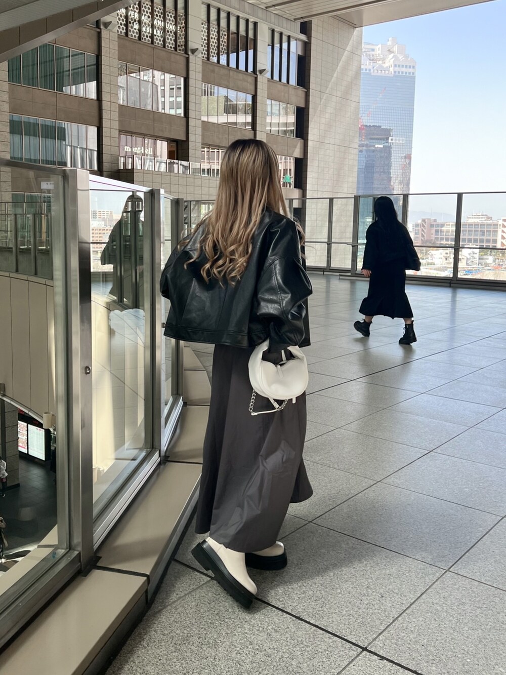 ブラック系のブルゾン、ブラウン系のニット/セーター、グレー系のスカートを着用したレディースの春コーディネートの3枚目の写真