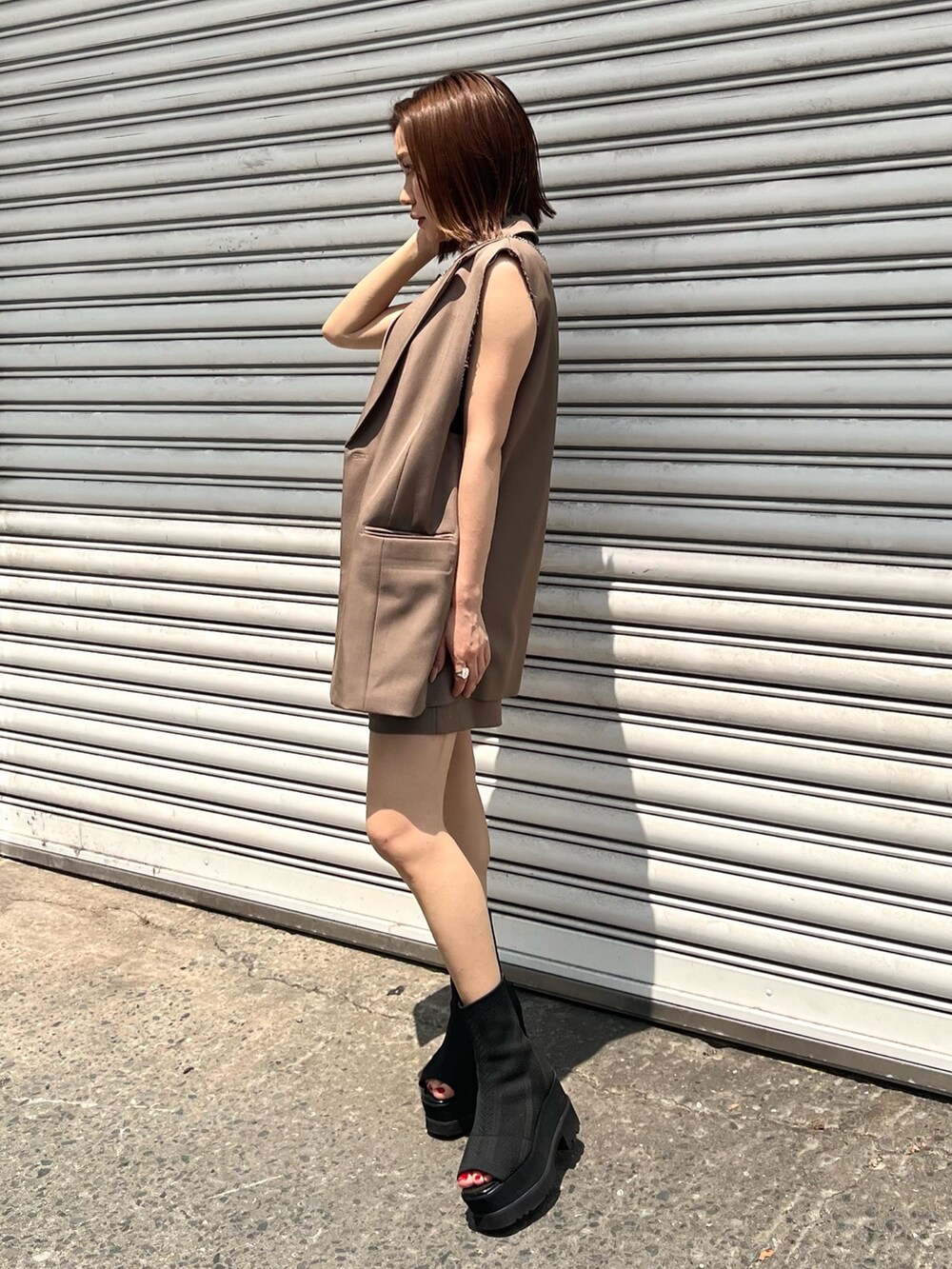 ブラウン系のベスト、ブラウン系のその他パンツ、ブラック系のキャミソールを着用したレディースの夏コーディネートの2枚目の写真