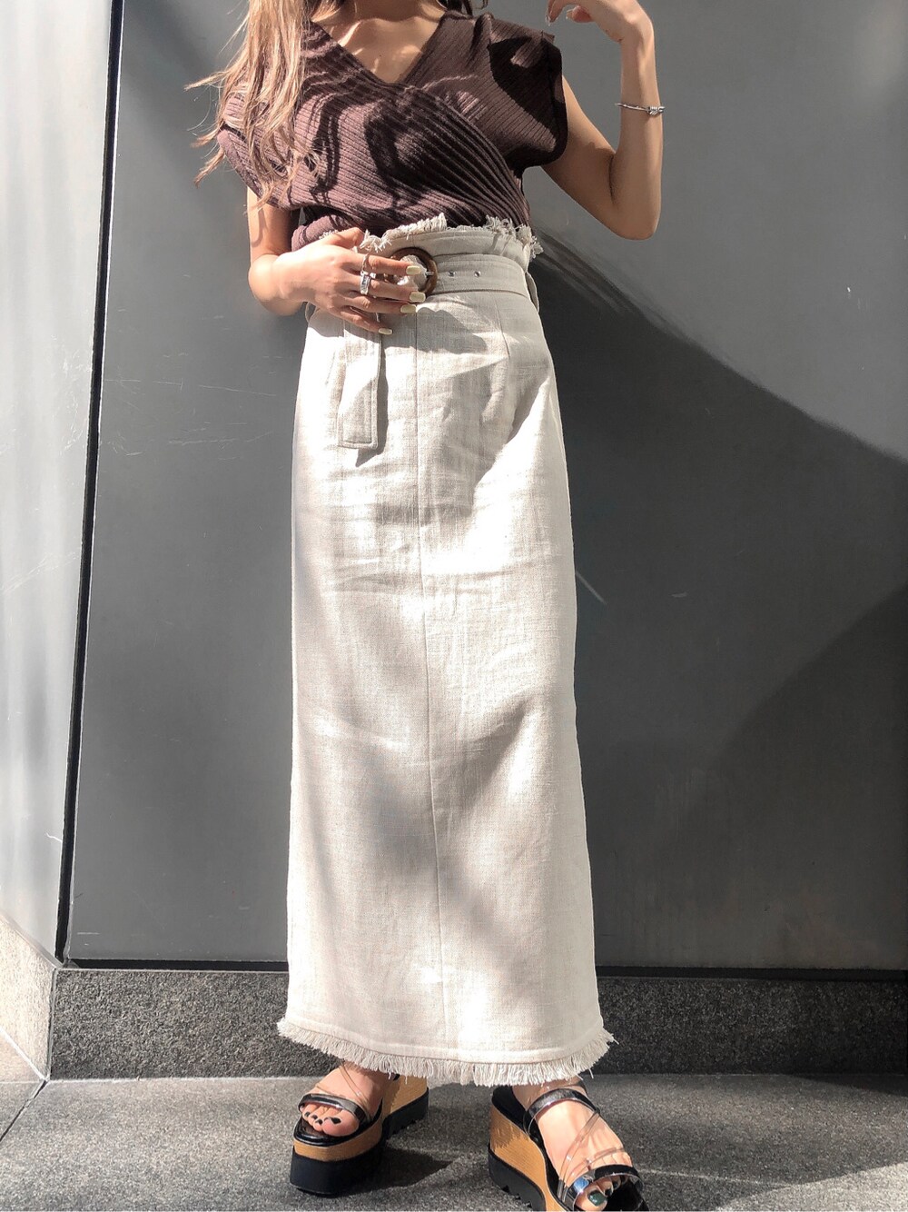 ホワイト系のスカート、ブラック系のサンダル、ブラウン系のニット/セーターを着用したレディースの春コーディネートの2枚目の写真