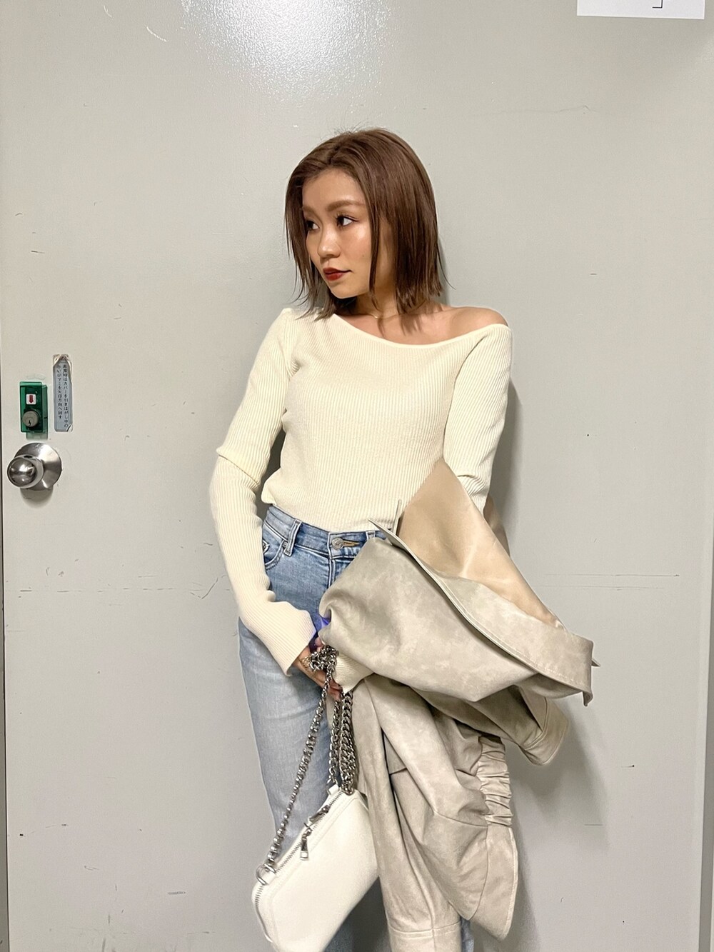 ホワイト系のブルゾン、ホワイト系のニット/セーター、ホワイト系のハンドバッグを着用したレディースの冬コーディネートの7枚目の写真