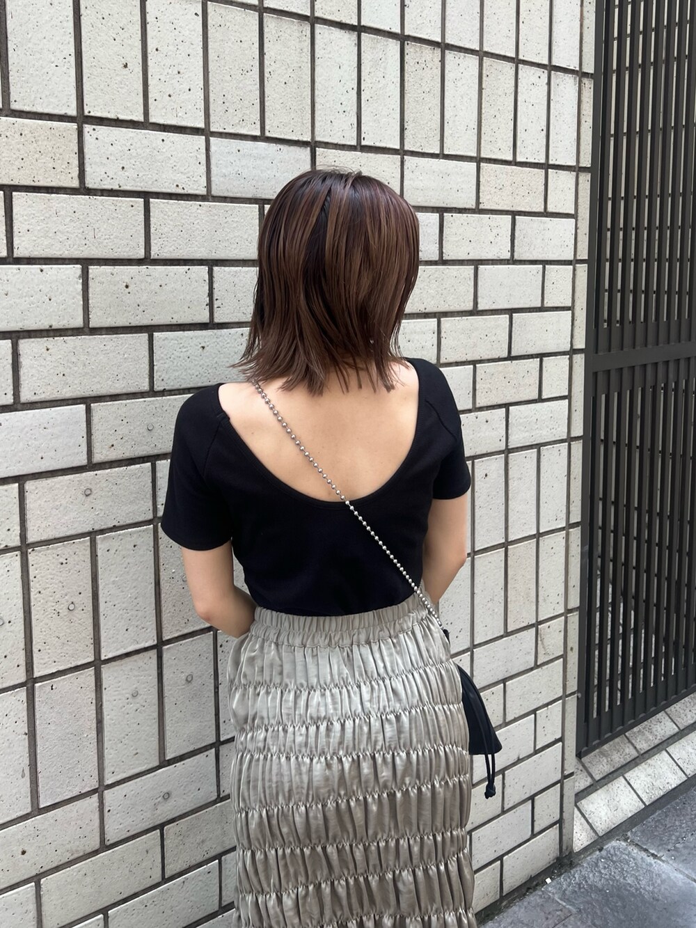 ブラック系のTシャツ/カットソー、グリーン系のスカート、ブラック系のショルダーバッグを着用したレディースの夏コーディネートの5枚目の写真