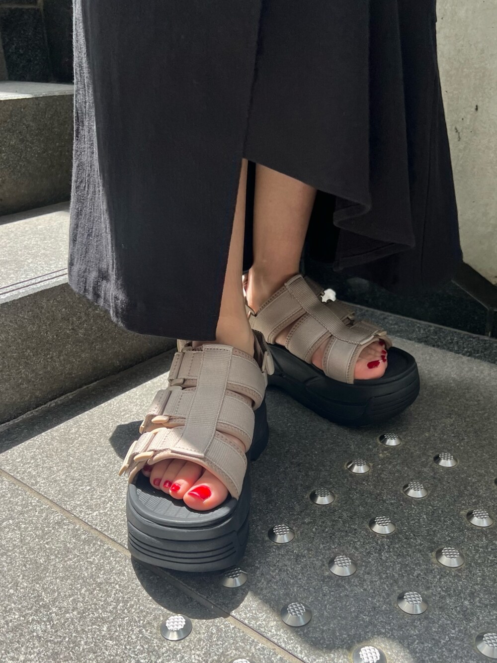 ブラック系のスカート、ブラック系のタンクトップ、ブラウン系のサンダルを着用したレディースの春コーディネートの8枚目の写真