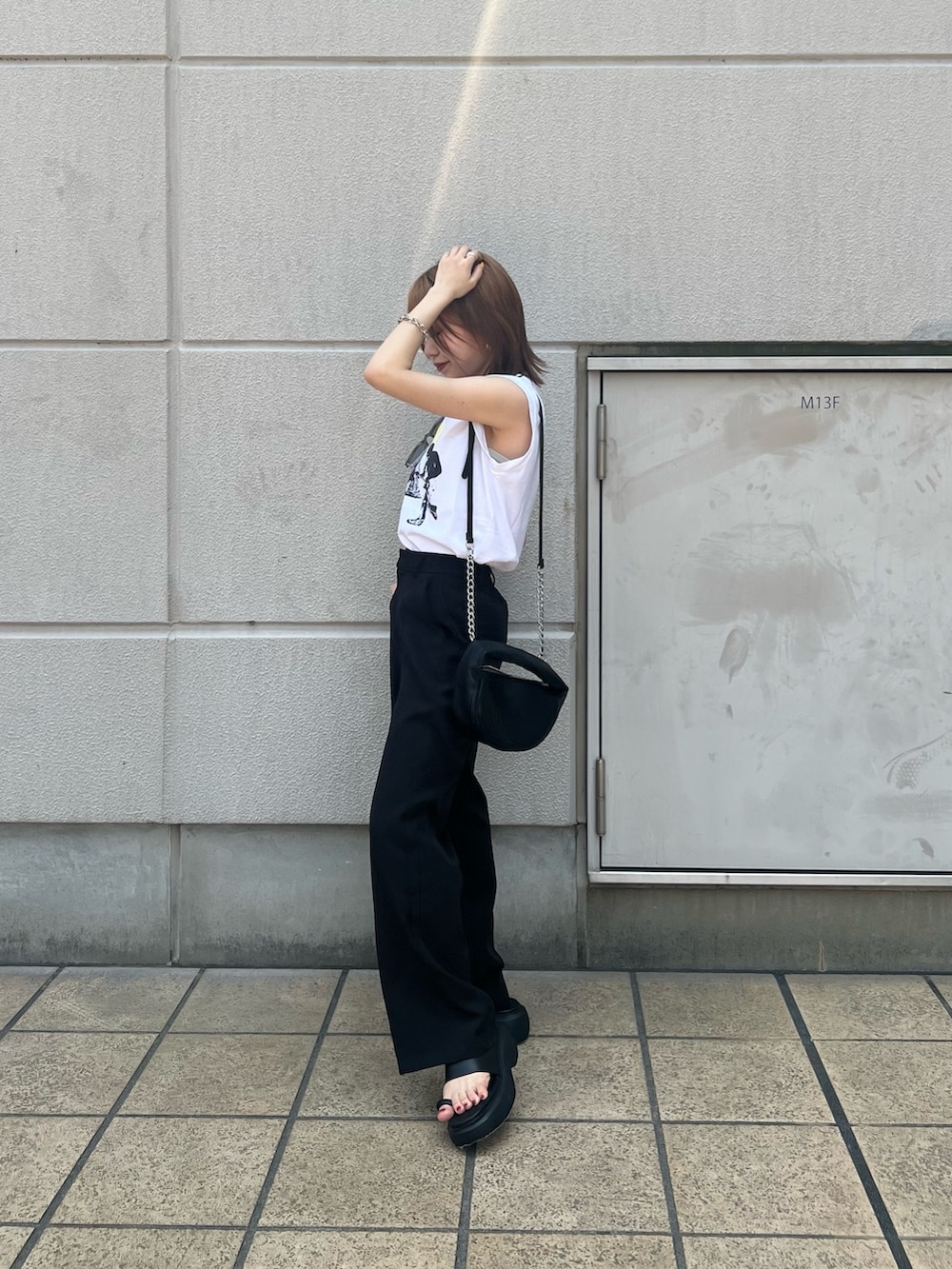 ホワイト系のタンクトップ、ブラック系のハンドバッグ、ブラック系のサンダルを着用したレディースの春コーディネートの3枚目の写真