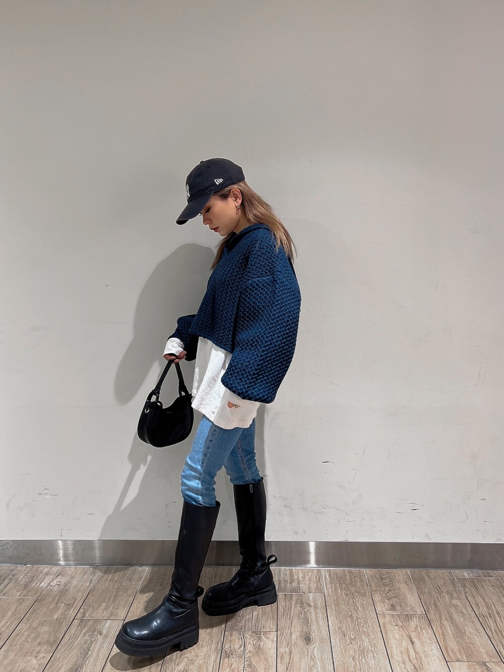ブラック系のブーツ、ブルー系のニット/セーター、ブラック系のハンドバッグを着用したレディースの冬コーディネートの4枚目の写真