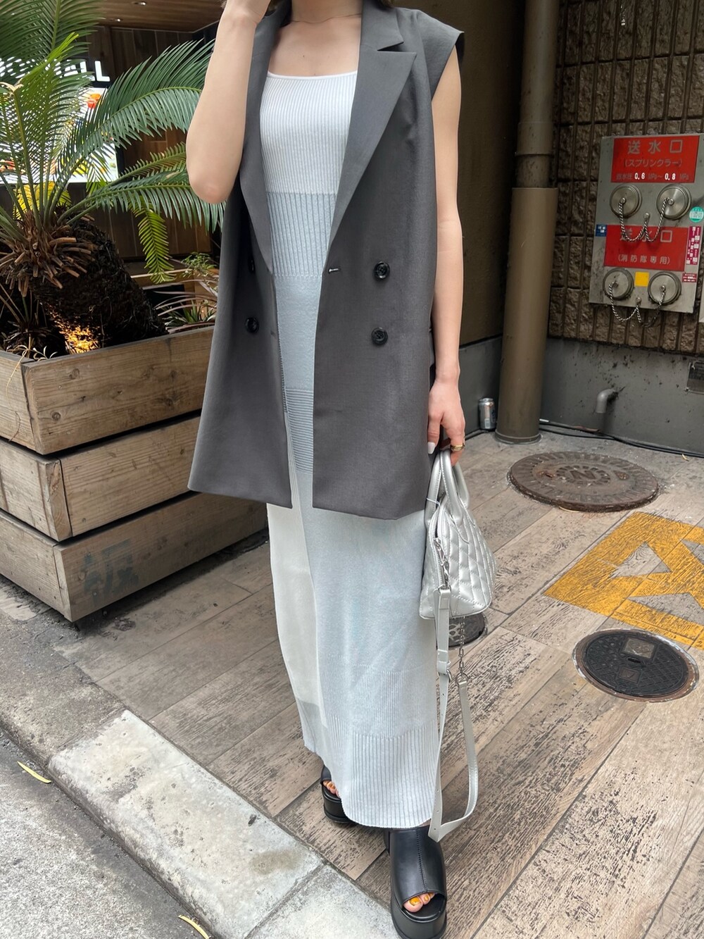 ホワイト系のワンピース、グレー系のベスト、ブラック系のサンダルを着用したレディースの春コーディネートの6枚目の写真