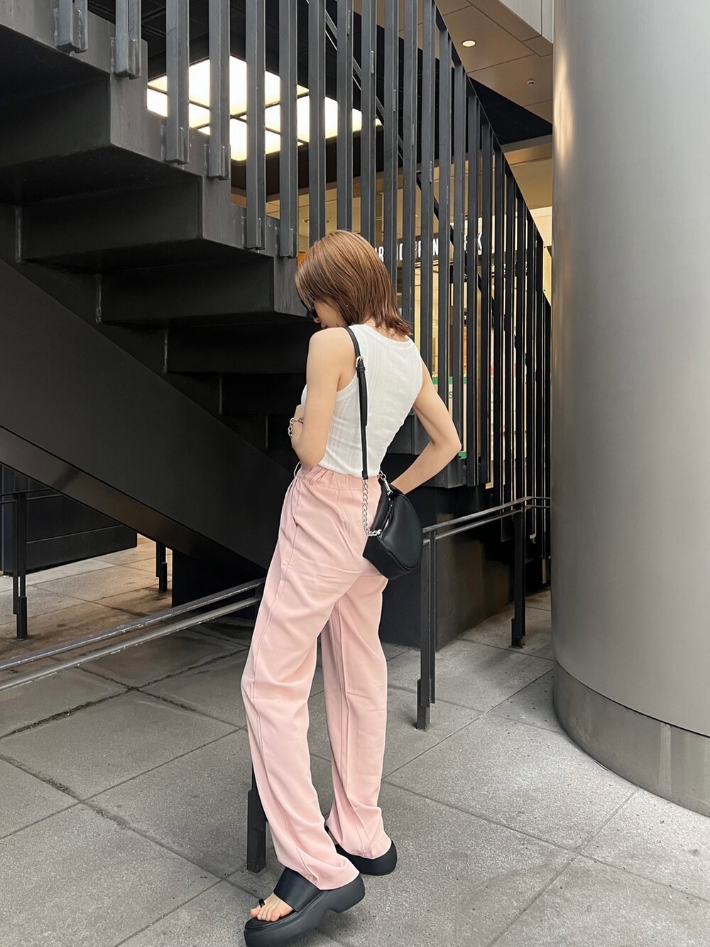 ブラック系のサンダル、ブラック系のハンドバッグ、ホワイト系のTシャツ/カットソーを着用したレディースの夏コーディネートの2枚目の写真