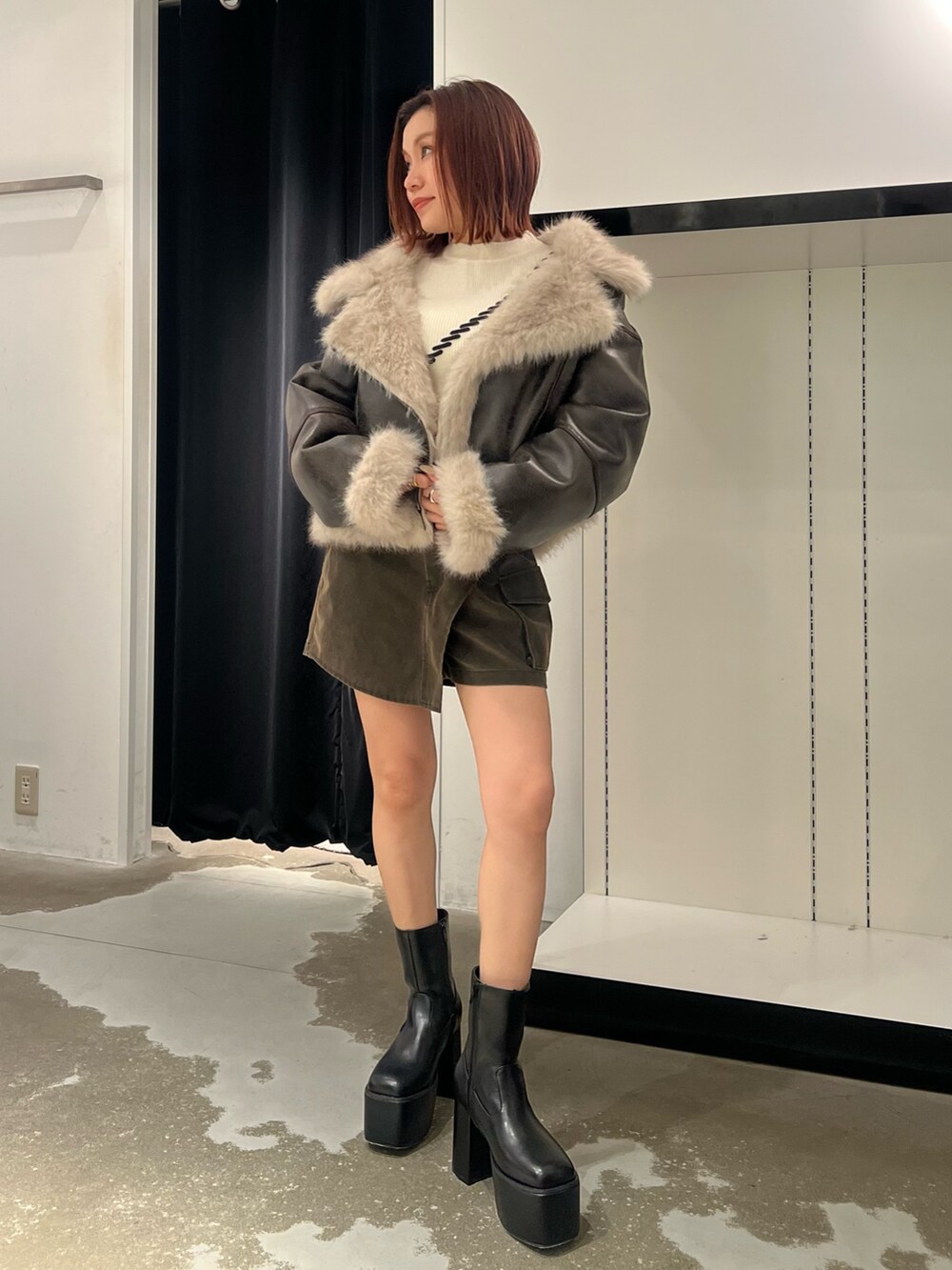 ブラウン系のムートンコート、ホワイト系のニット/セーター、ブラウン系のその他パンツを着用したレディースの秋コーディネートの4枚目の写真