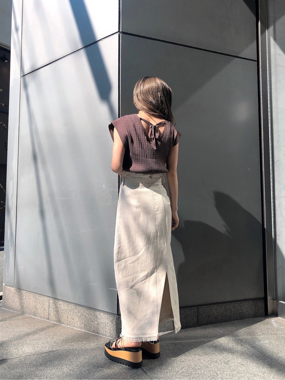 ホワイト系のスカート、ブラック系のサンダル、ブラウン系のニット/セーターを着用したレディースの春コーディネートの4枚目の写真