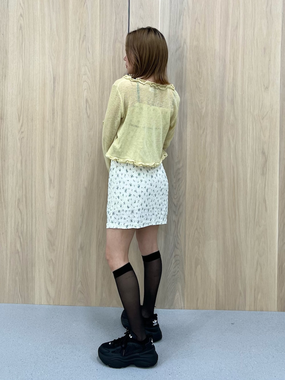 イエロー系のニット/セーター、ホワイト系のワンピースを着用したレディースの春コーディネートの2枚目の写真