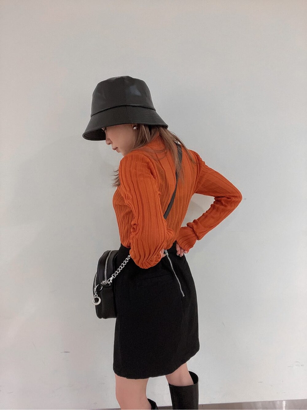 ブラック系のブーツ、オレンジ系のニット/セーター、ブラック系のスカートを着用したレディースの秋コーディネートの5枚目の写真