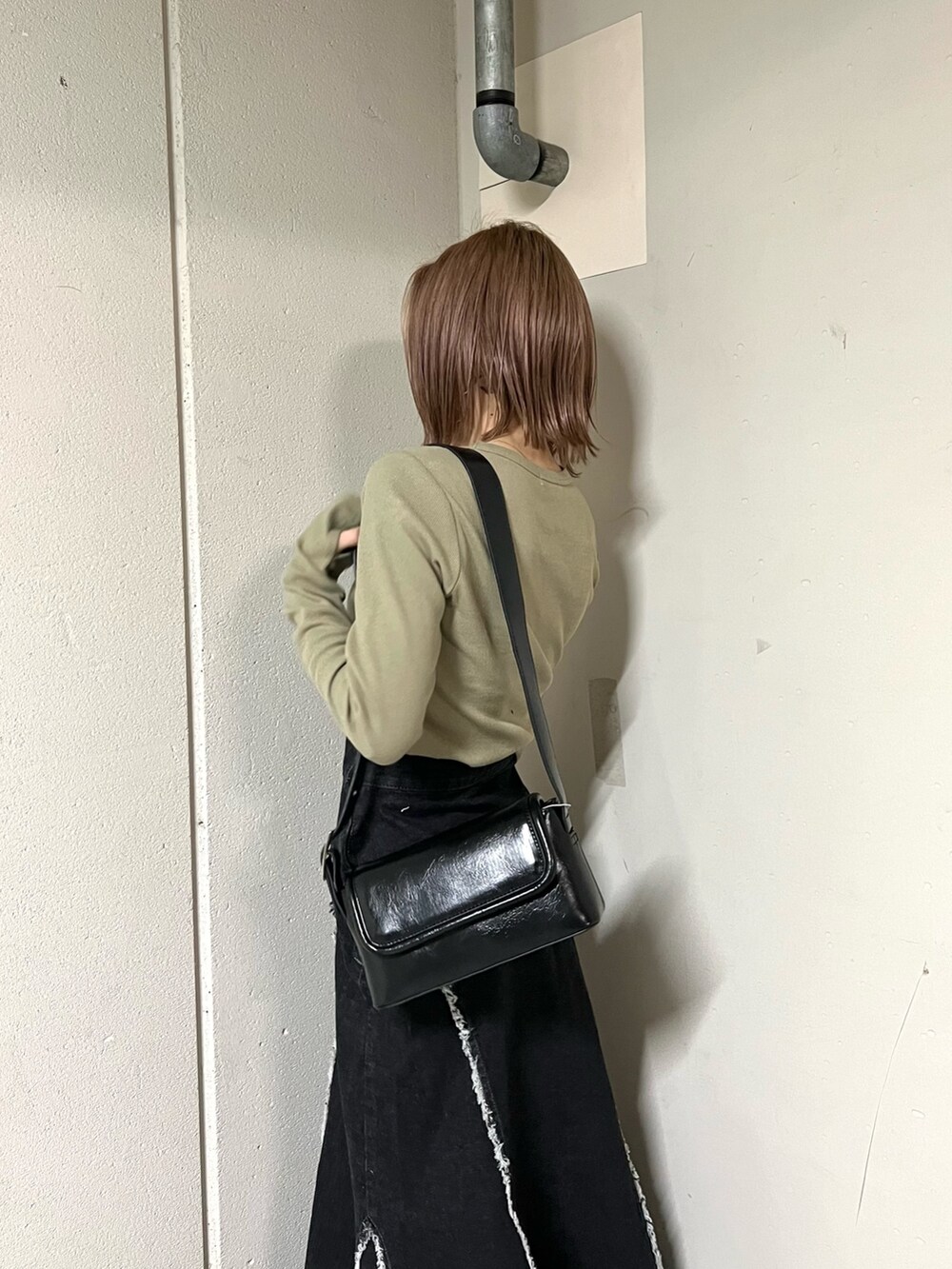 グリーン系のTシャツ/カットソー、ブラック系のデニムスカート、ブラック系のブーツを着用したレディースの冬コーディネートの5枚目の写真