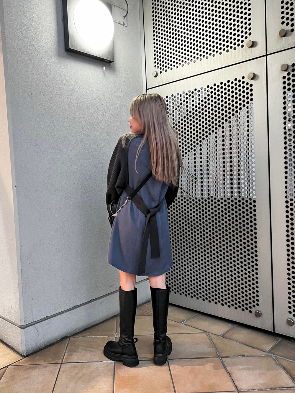 グレー系のワンピース、ブラック系のショルダーバッグ、ブラック系のブーツを着用したレディースの冬コーディネートの2枚目の写真