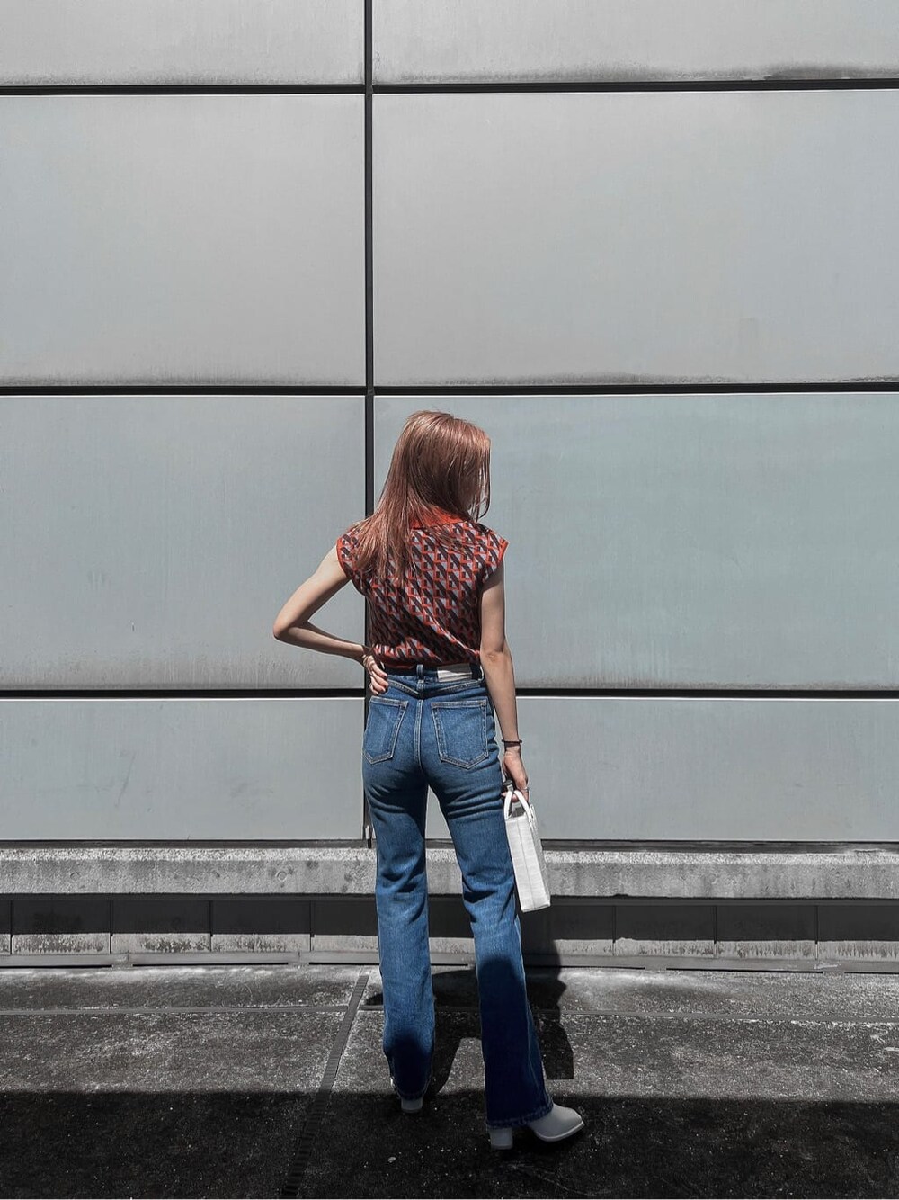 ブルー系のデニムパンツ、オレンジ系のニット/セーター、ホワイト系のブーツを着用したレディースの夏コーディネートの5枚目の写真