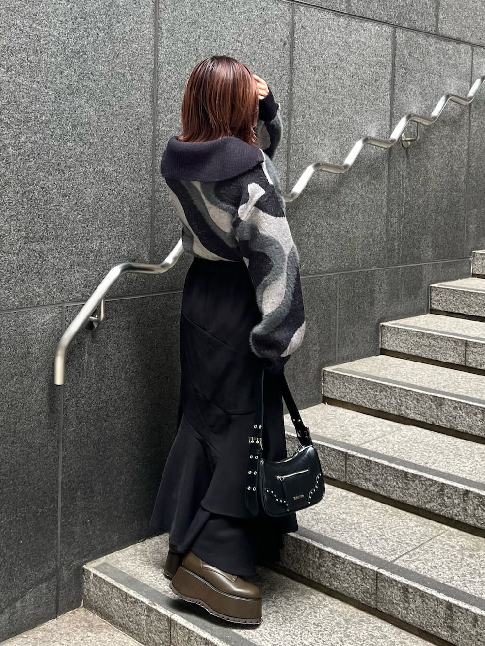 ブラック系のニット/セーター、ブラウン系のブーツ、ブラック系のスカートを着用したレディースの秋コーディネートの2枚目の写真