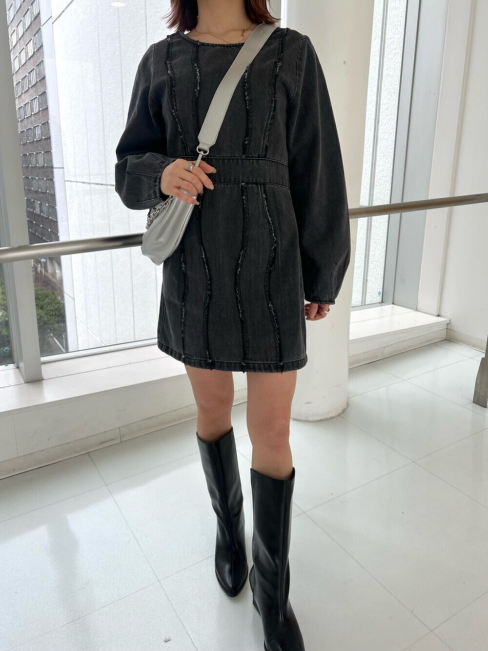 シルバー系のショルダーバッグ、ブラック系のワンピース、ブラック系のブーツを着用したレディースの冬コーディネートの6枚目の写真