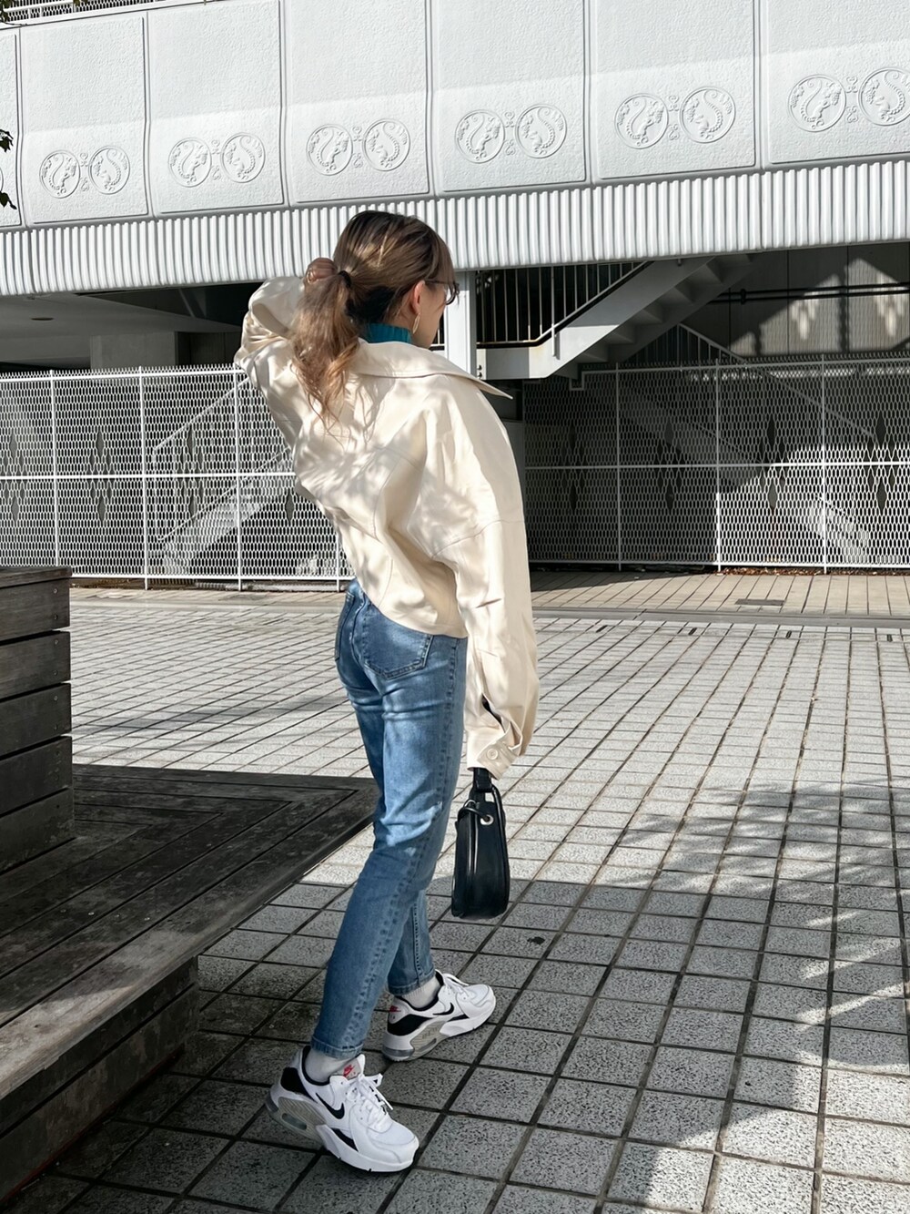 ホワイト系のライダースジャケット、ブルー系のニット/セーター、ブラック系のハンドバッグを着用したレディースの冬コーディネートの2枚目の写真