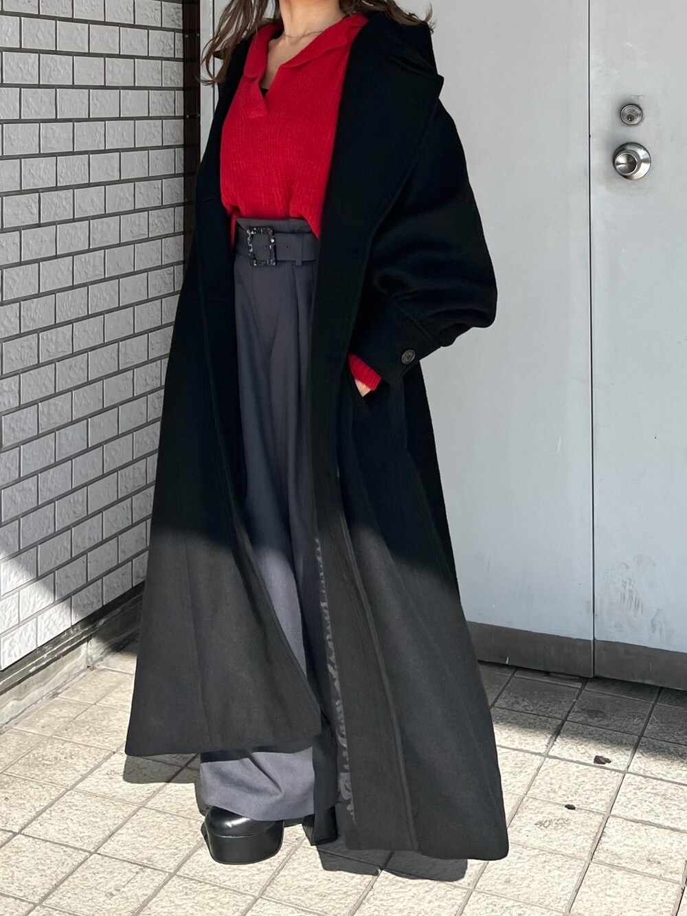 レッド系のニット/セーター、ブラック系のダウンジャケット/コート、ブラック系のブーツを着用したレディースの秋コーディネートの5枚目の写真