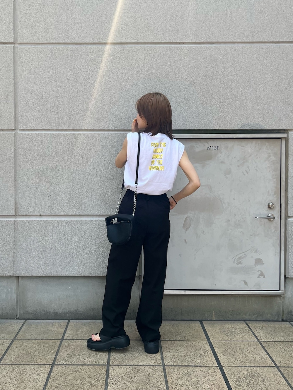 ホワイト系のタンクトップ、ブラック系のハンドバッグ、ブラック系のサンダルを着用したレディースの春コーディネートの2枚目の写真