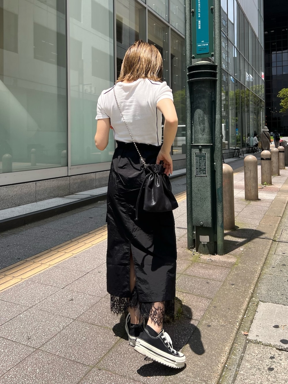 ブラック系のスカート、ブラック系のショルダーバッグ、ホワイト系のTシャツ/カットソーを着用したレディースの夏コーディネートの3枚目の写真