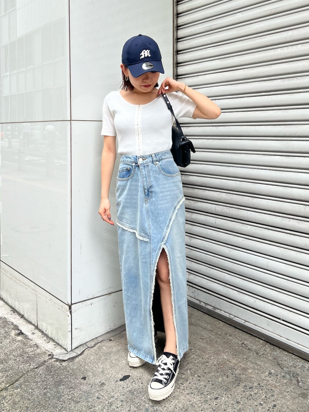 ホワイト系のニット/セーター、ブルー系のデニムスカート、ブラック系のハンドバッグを着用したレディースの夏コーディネートの4枚目の写真