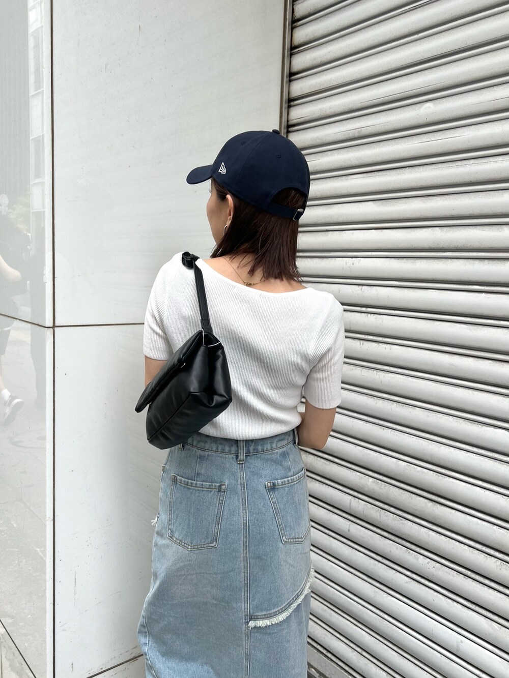 ホワイト系のニット/セーター、ブルー系のデニムスカート、ブラック系のハンドバッグを着用したレディースの夏コーディネートの6枚目の写真