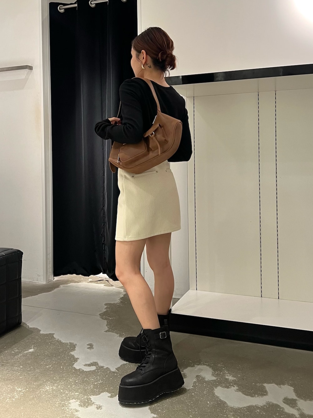 ホワイト系のスカート、ブラック系のTシャツ/カットソー、ブラック系のブーツを着用したレディースの秋コーディネートの2枚目の写真