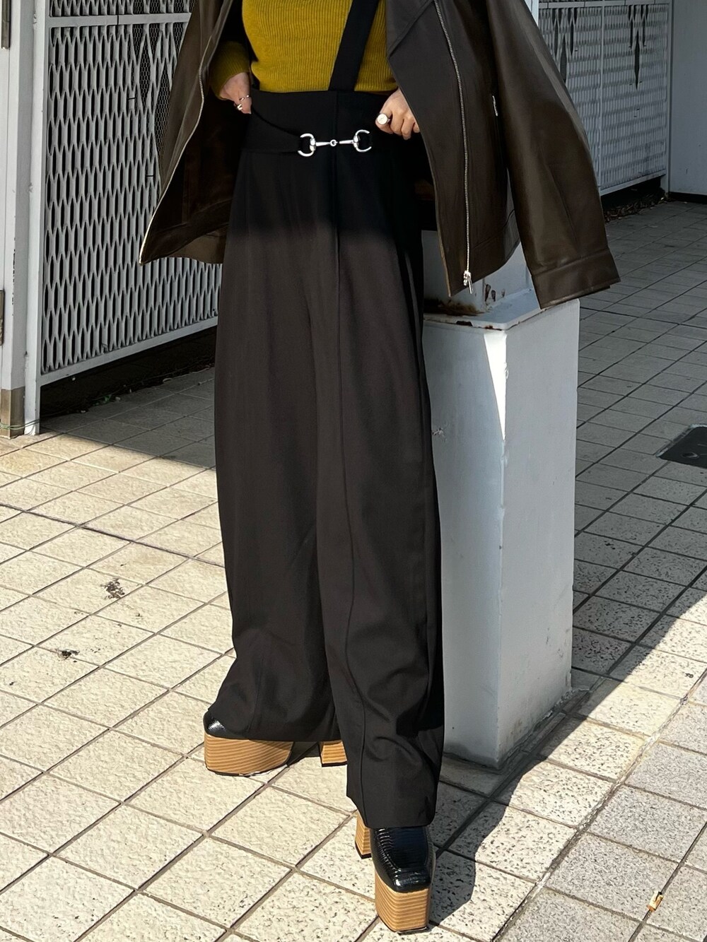 ブラウン系のライダースジャケット、ブラック系のスラックス、ブラック系のローファーを着用したレディースの秋コーディネートの4枚目の写真