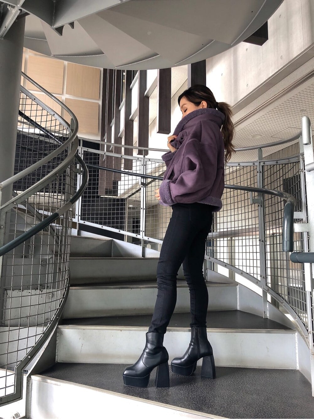 ブラック系のブーツ、パープル系のブルゾン、ブラック系のニット/セーターを着用したレディースの秋コーディネートの2枚目の写真