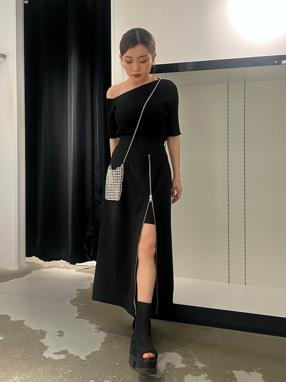 ブラック系のスカート、ブラック系のサンダル、シルバー系のショルダーバッグを着用したレディースの春コーディネートの2枚目の写真