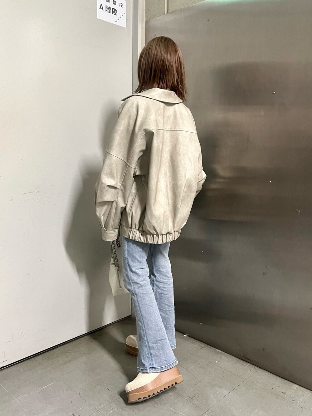 ホワイト系のブルゾン、ホワイト系のニット/セーター、ホワイト系のハンドバッグを着用したレディースの冬コーディネートの4枚目の写真