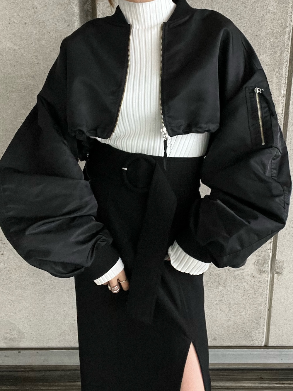 ブラック系のMA-1、ホワイト系のニット/セーター、ブラック系のスカートを着用したレディースの冬コーディネートの7枚目の写真