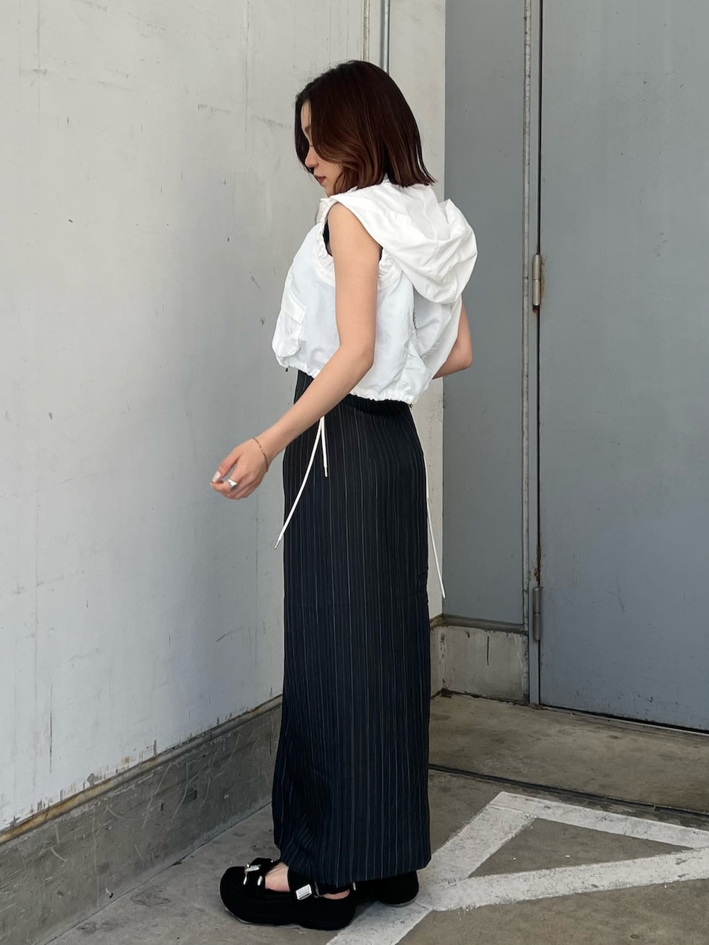 ホワイト系のベスト、ブラック系のタンクトップ、グレー系のスカートを着用したレディースの春コーディネートの2枚目の写真